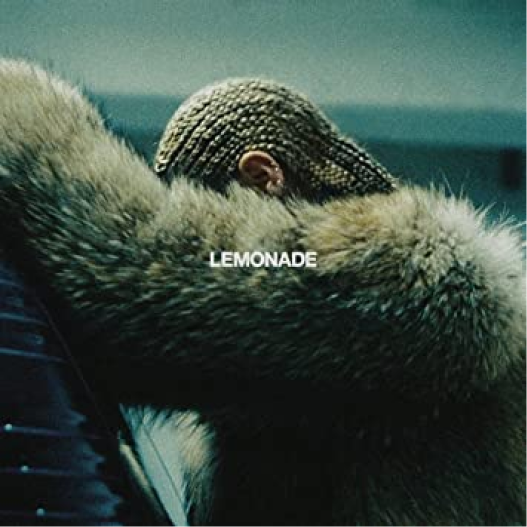 Capa do álbum Lemonade, de Beyoncé, que mostra a artista de perfil apoiada sobre um carro com um casaco de pele e boxbraids. Não conseguimos ver seu rosto. Lemos o título do álbum, 'Lemonade' em pequenas letras brancas no centro da capa.